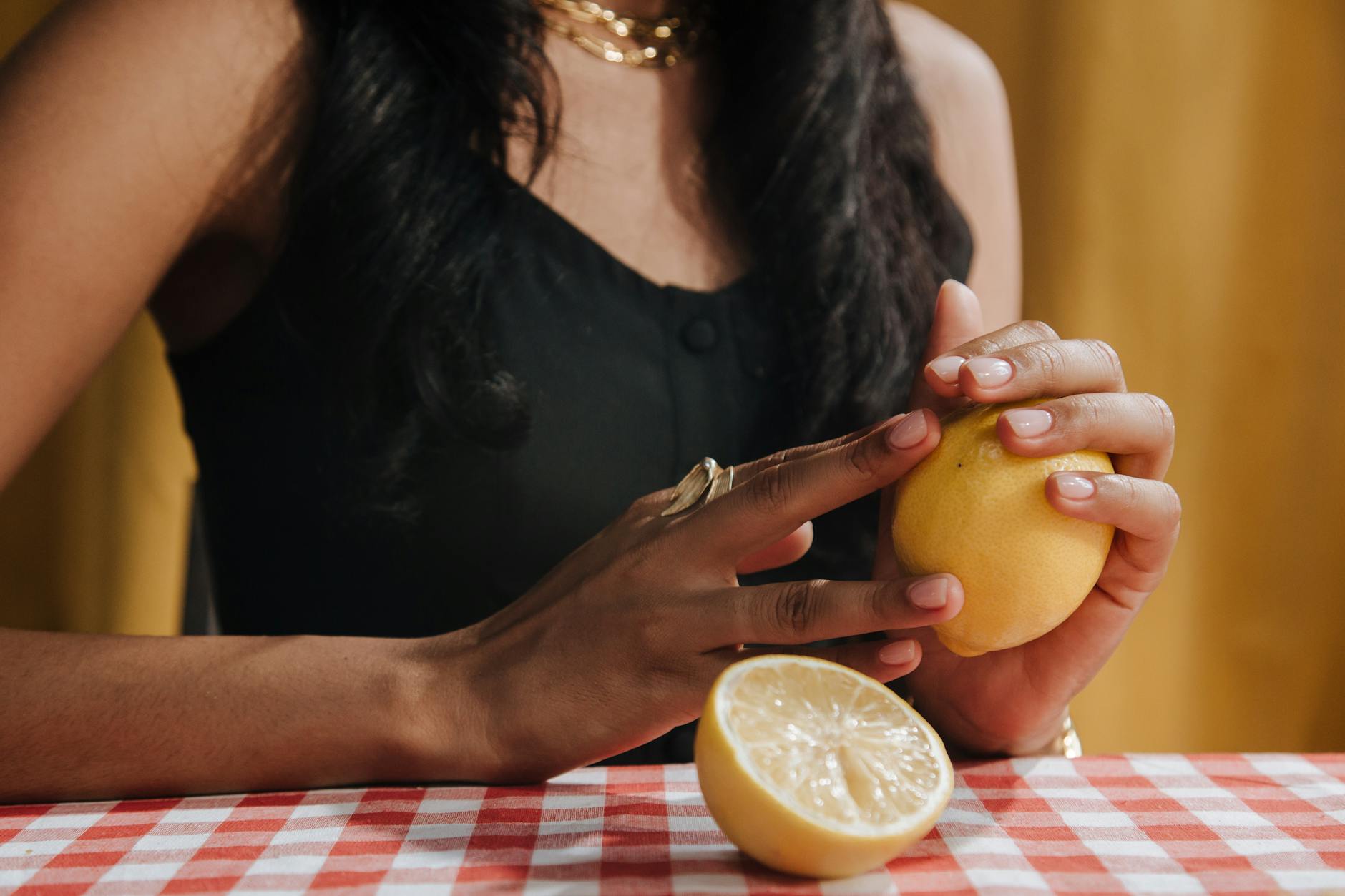 A woman with dark hair holding a fresh lemon at a dining table, symbolizing natural vitality and renewal