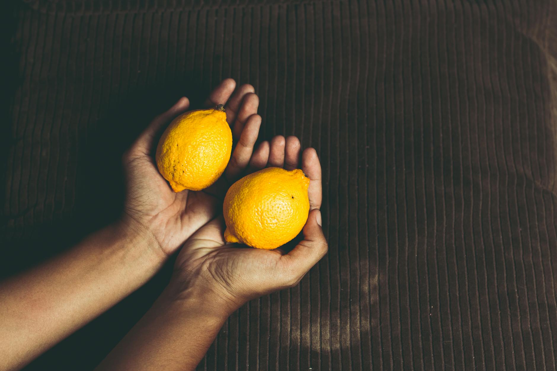 Due limoni freschi tenuti in mani a coppa su una superficie marrone, simbolo di rinascita e ritorno della sensibilità