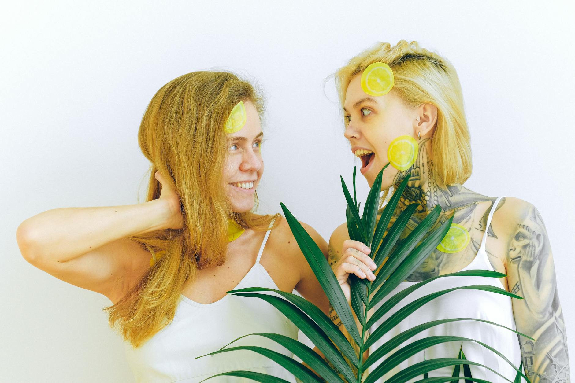 Two women smiling and holding fresh lemons, expressing joy and comfort with natural intimacy