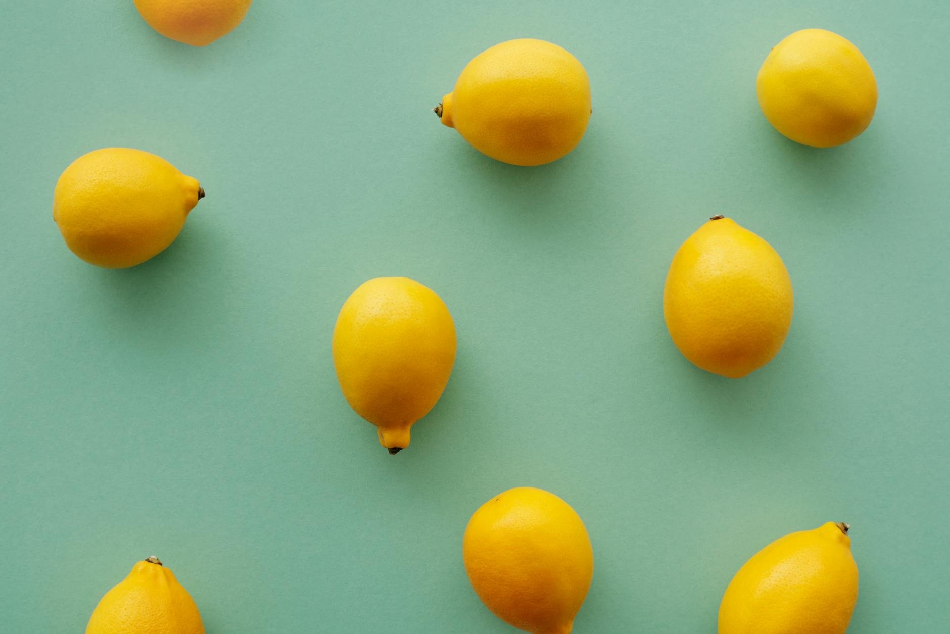 Bright yellow lemons on a pastel green background, representing fresh sensation and new pleasure discovery