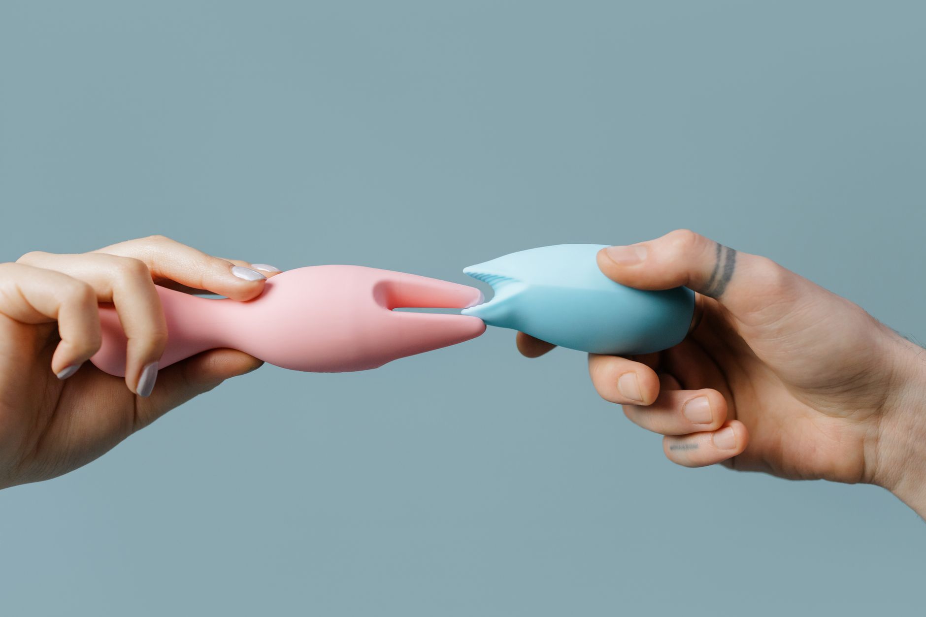 Hands holding a sleek blue vibrator against a purple background