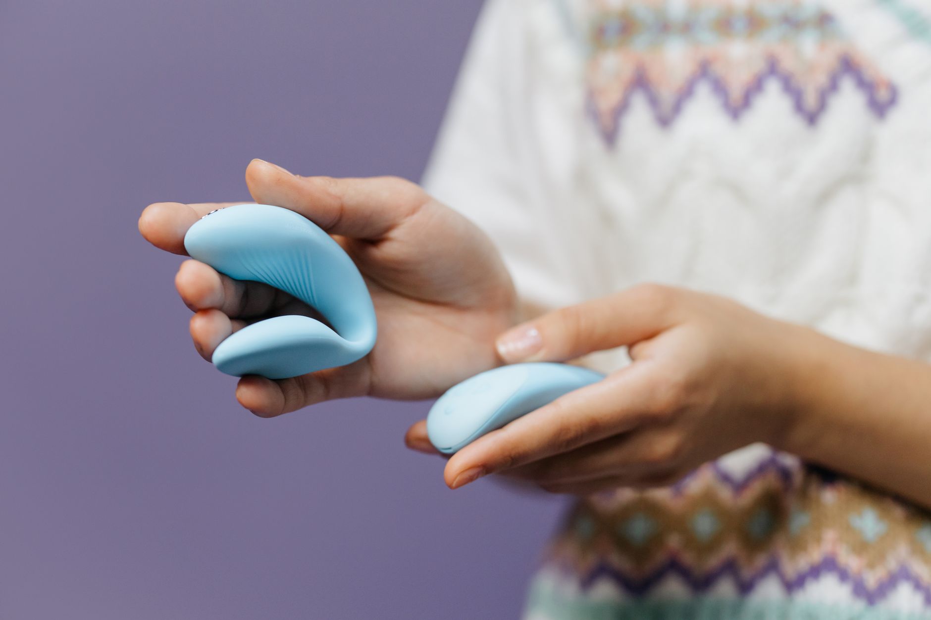 Donna con occhiali che tiene un vibratore blu e rosa in modo contemplativo