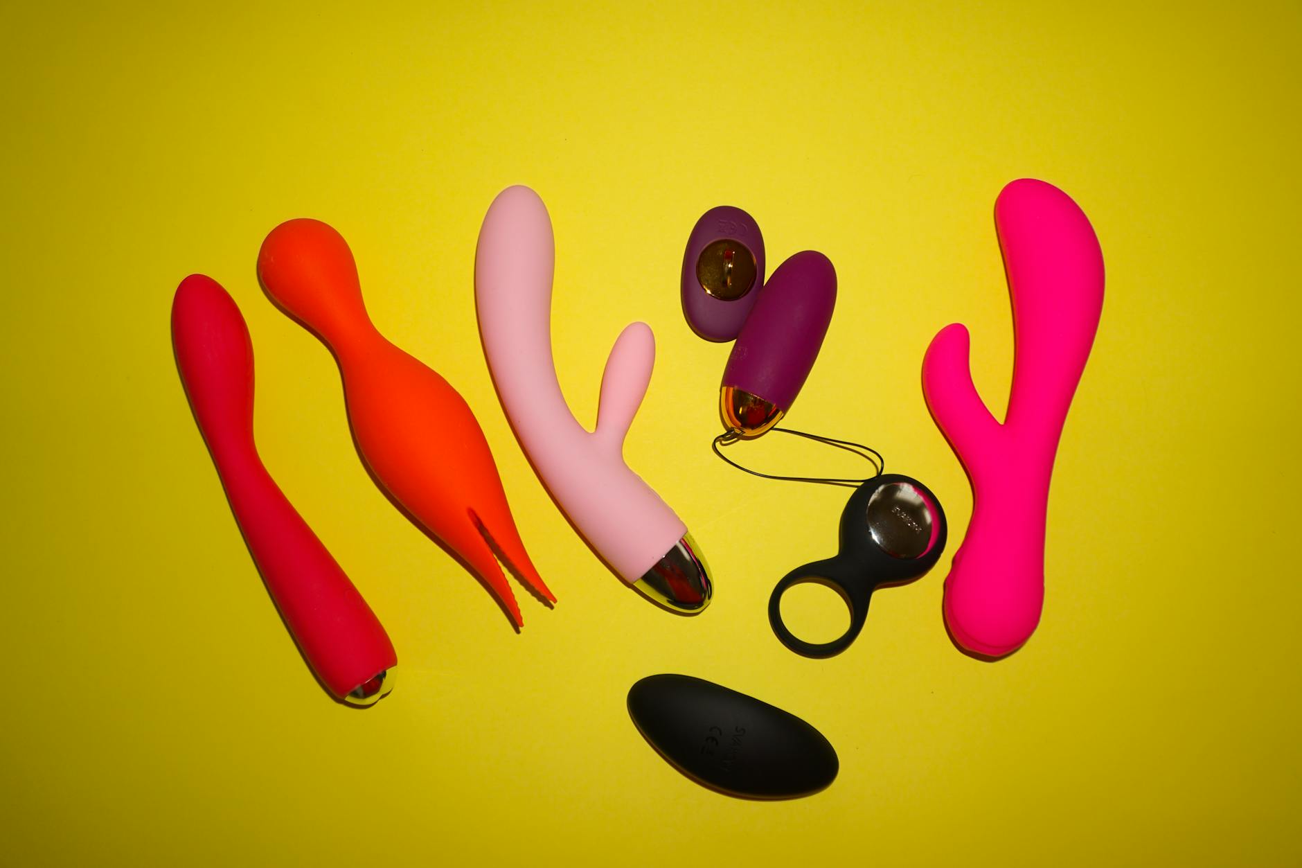 Colorful sex toys including lemon vibrators displayed on a bright yellow background